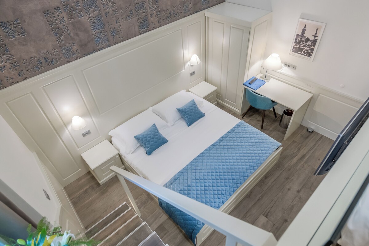 A bedroom with a bed, bedside tables, a desk, and a chair.