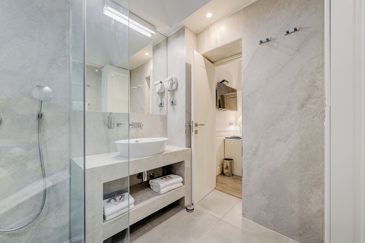 A modern bathroom with a glass-enclosed shower, a white sink, and a mirror.