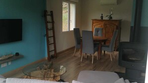 A living room with a sofa set, a coffee table, a TV mounted on the wall, a dining area with chairs and a table, and a fireplace. - Maison de Campagne (Larrivière-Saint-Savin)