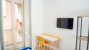 A room with a bed, a desk, and a TV. - Vulcania Rooms (Naples)