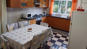 A compact kitchen with wooden cabinets, a microwave, stove, and a dining table with chairs.
