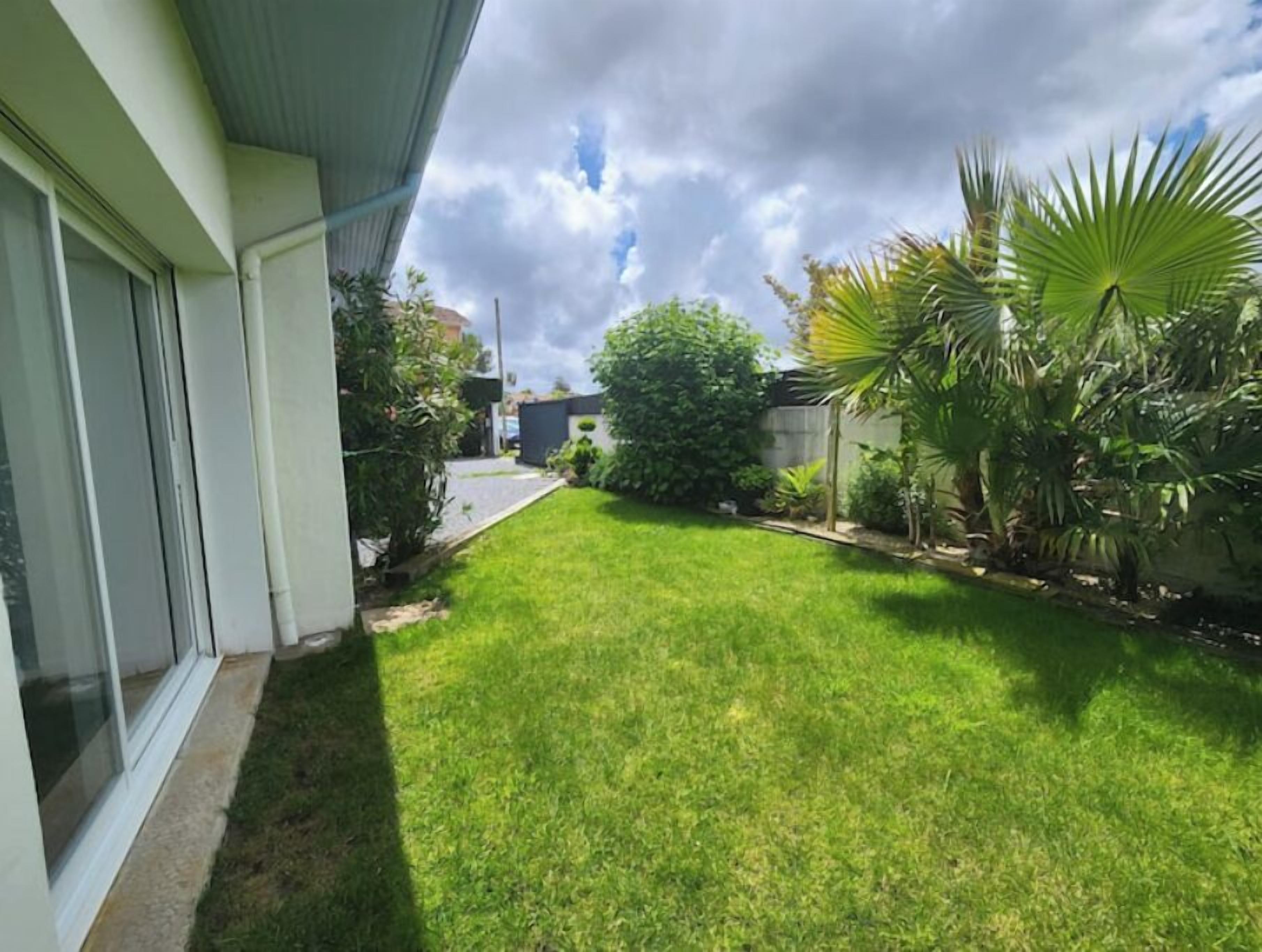 A residential property with a well-maintained lawn, a pathway leading to the house, and a variety of plants and trees.