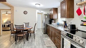 Une cuisine compacte avec des meubles en bois, un four encastré et un coin repas comprenant une table et des chaises.