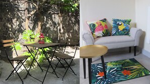 Eine Terrasse mit Tisch und Stühlen, eine Sitzecke mit tropischen Kissen und einem dekorativen Teppich.