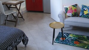 Ein gemütlicher Wohnraum mit Küchenzeile, einem Essbereich mit Tisch und Stühlen sowie einer Couch mit Zierkissen.