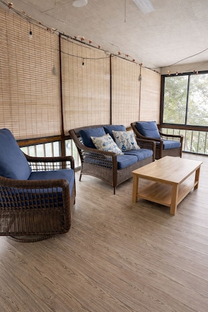 A room with wicker furniture, including a sofa and chairs, a wooden coffee table, and bamboo blinds. - Spacious Condo•Pond Views•Centrally located (Lewes)