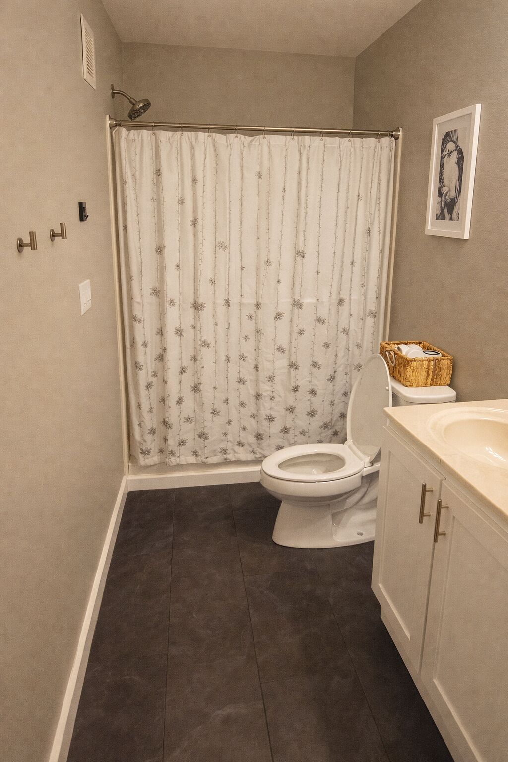 Une salle de bain avec un rideau de douche, des toilettes, un lavabo et un tableau encadré au mur.