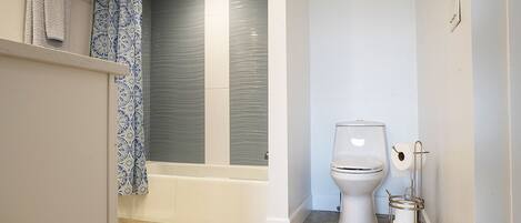 Un baño con bañera, inodoro y barra para toallas.