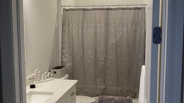 A bathroom with a double sink vanity, a toilet, a shower curtain, and a towel rack. - New beautiful Pool .  May thru Dec 2025 $2599 a month.  $87a night. Contact Pam  (Rotonda West)