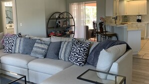 A modern living room with a sectional sofa, a glass coffee table, and a ceiling fan. - South Venice Hidden Gem (Venice)