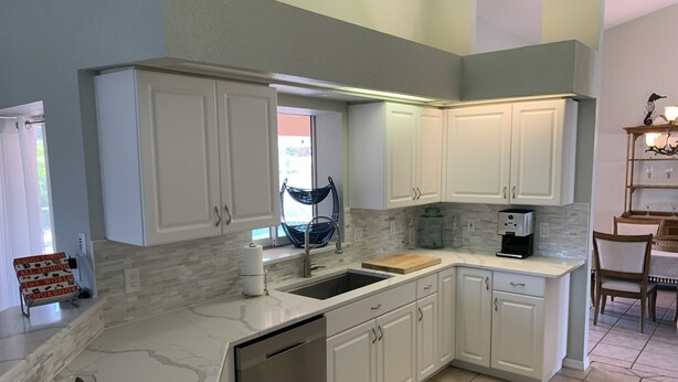 A modern kitchen with white cabinets, a dishwasher, a sink, and a coffee maker. - South Venice Hidden Gem (Venice)