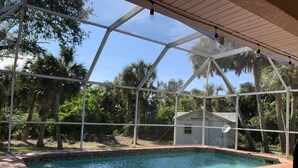 A swimming pool with a glass enclosure, surrounded by palm trees and a small building labeled "TRANQUILITY". - South Venice Hidden Gem (Venice)