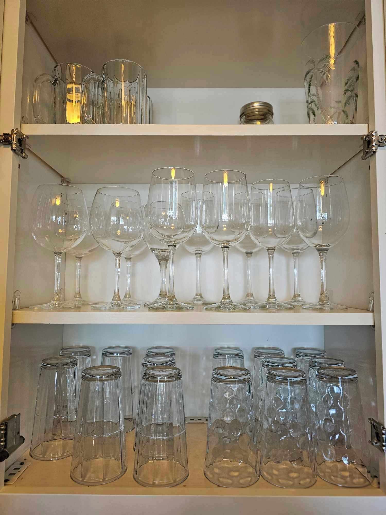 Un meuble de rangement doté d’étagères où sont rangés divers articles en verre, notamment des verres à vin et des verres à cocktail.