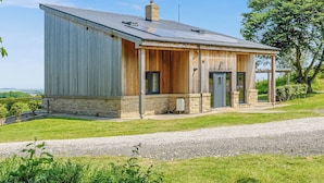 Une maison de plain-pied avec un toit en métal, un revêtement en bois et des fondations en pierre.