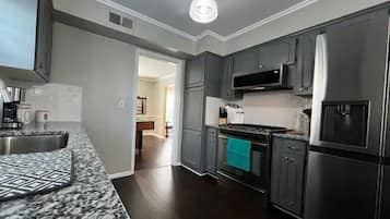Une cuisine moderne avec des meubles de couleur sombre, des appareils en acier inoxydable et un dosseret décoré.