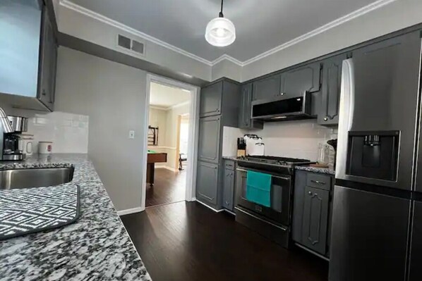 A modern kitchen with dark cabinets, stainless steel appliances, and a patterned backsplash.