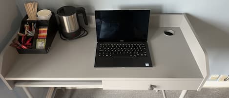 Een laptop op een bureau met een beker, stokjes en een doosje snacks.