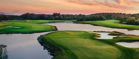 A golf course with water hazards, sand bunkers, and a flag on the green.