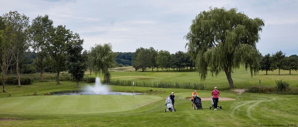 A golf course with a pond, trees, and a fountain. - Lynge Kro & Hotel (Lynge)