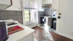 Une cuisine moderne équipée d’un four encastré, d’un four à micro-ondes et d’une fenêtre avec des stores.