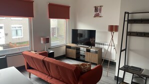 Una sala de estar moderna con un sofá, televisor y una mesita.
