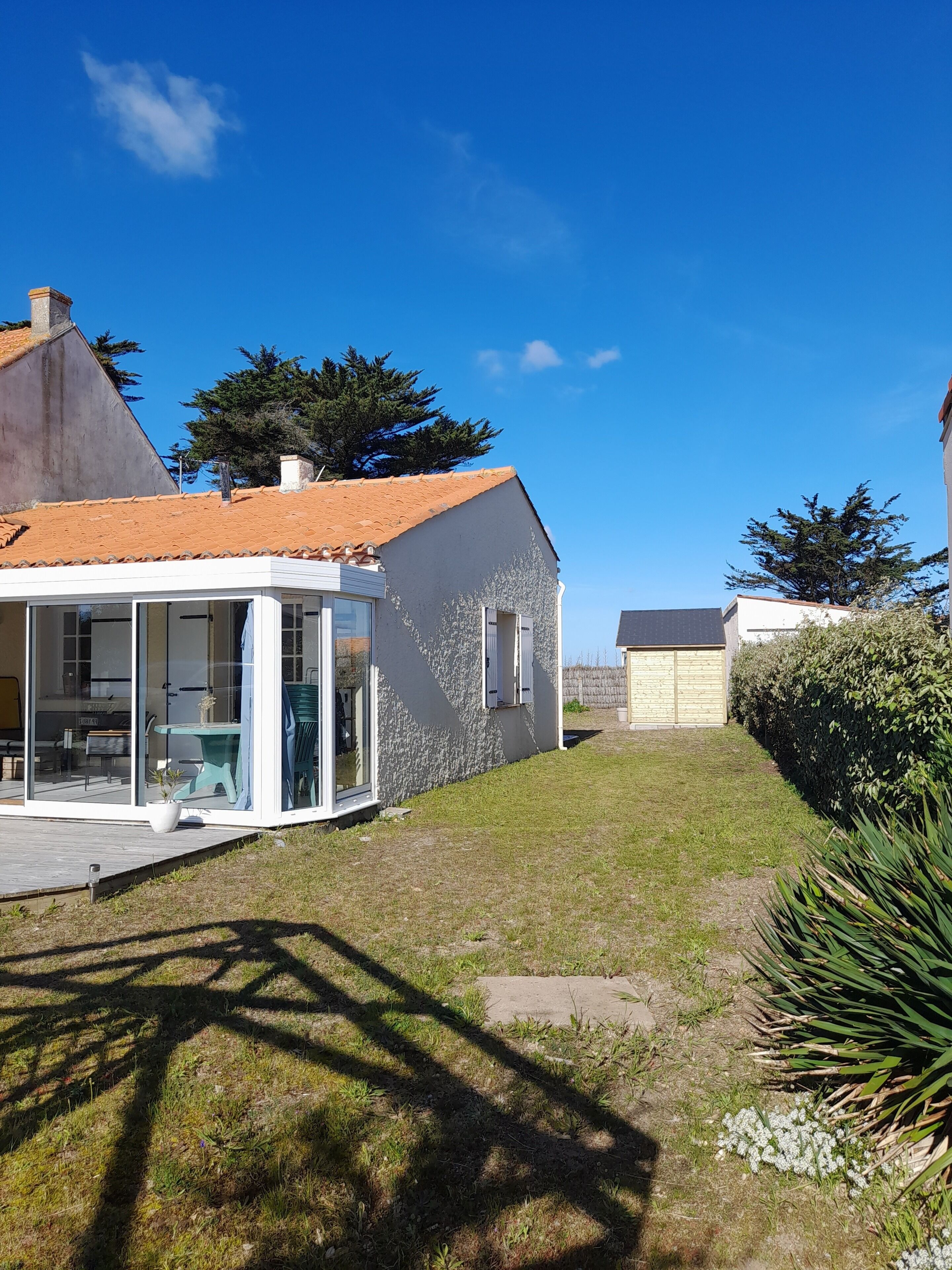 Une maison moderne dotée d’un patio entièrement vitré, d’un toit en tuiles et d’une pelouse bien entretenue.