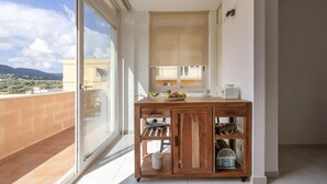Ein Balkon mit Holztisch, einem Fenster und Blick auf die Landschaft.