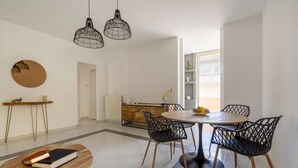 Ein stilvoller Essbereich mit einem runden Tisch und vier Stühlen, einer Holzkonsole mit Spiegel und einem kleinen, runden Tisch mit Büchern.
