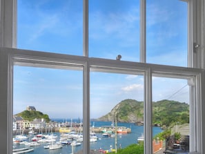 A harbor with boats, a hill with a building, and a clear sky.
