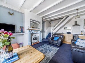 A living room with a fireplace, a sofa, a coffee table, and a TV. - 1 bedroom accommodation in Ilfracombe (Ilfracombe)