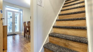 A staircase with wooden steps and carpeted edges, a door with a polite notice, and a view of a dining area with chairs and a table. - Totally refurbished cottage, decorated and equipped to a high standard. (Cornsay Colliery, Lanchester, Durham)