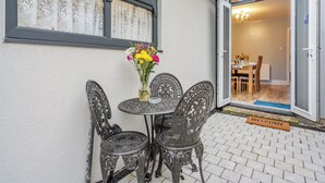 A patio with a table and chairs, a vase with flowers, and a door leading to an interior space. - Totally refurbished cottage, decorated and equipped to a high standard. (Cornsay Colliery, Lanchester, Durham)