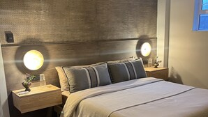 Un dormitorio moderno con una cama grande, dos mesitas de noche y una lámpara fijada a la pared.