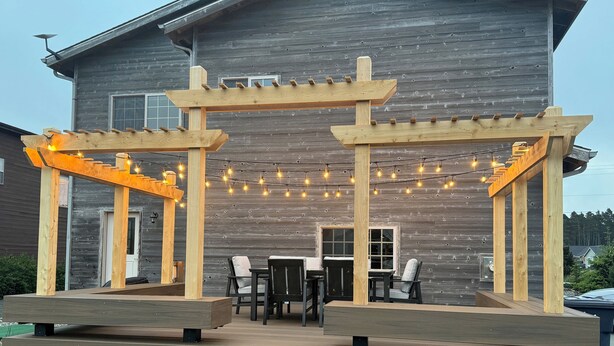 Una terraza de madera con asientos al aire libre y luces colgantes.