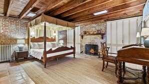 Une chambre à coucher avec un lit à baldaquin, une cheminée et un plafond en bois rustique.