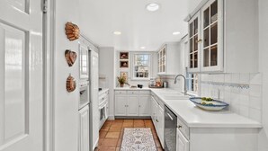 Une cuisine avec des meubles blancs, un pare-feu en carreaux et un tapis à motifs.