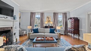 Un salon avec une cheminée, un canapé, une table basse et un meuble.
