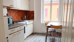 Een keuken met witte kastjes, een houten aanrechtblad en een raam met uitzicht op een gebouw.