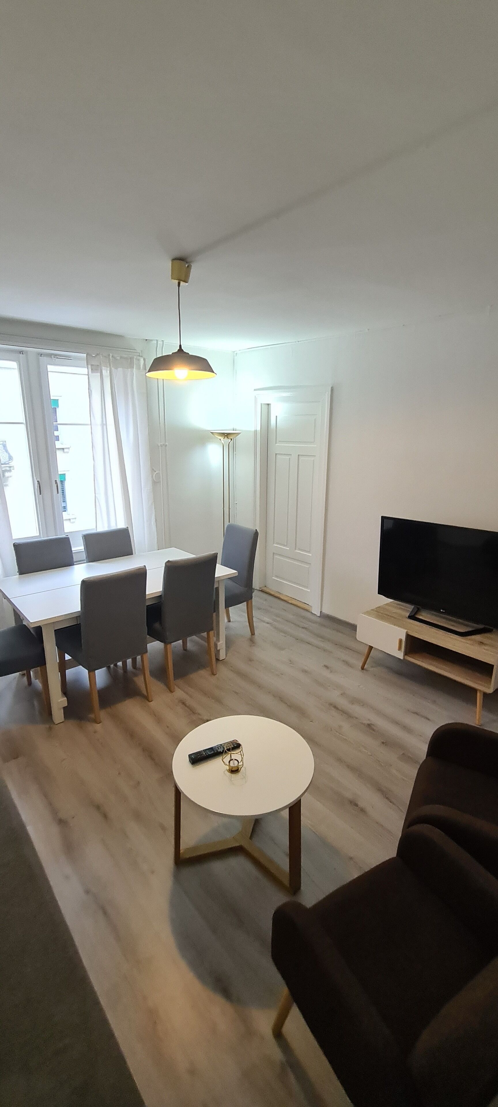 Un salon moderne comprenant un coin repas, un téléviseur et une table basse ronde.