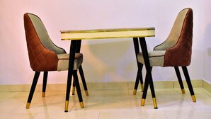 A dining table with two chairs, each with a quilted seat and black legs with gold accents. - Viola Apartments & Suites (Abuja)