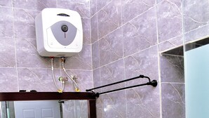 A bathroom with a marble-tiled wall, a white sink, a black cabinet, and a hand dryer mounted on the wall. - Viola Apartments & Suites (Abuja)