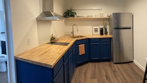 A modern kitchen with a stainless steel refrigerator, wooden countertop, and blue cabinets.