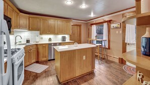 A kitchen with wooden cabinets, a central island, a stove, and a dishwasher.