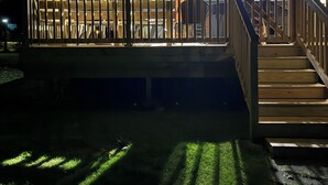 A house with a deck, a covered patio, and a staircase leading to the main building.