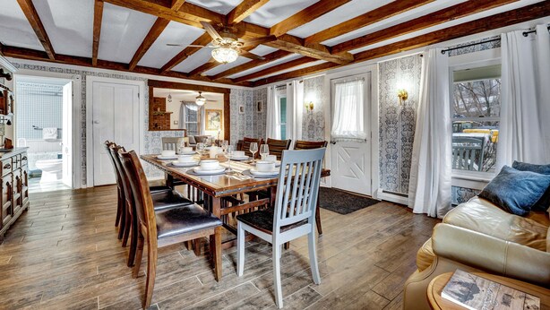 A dining area with a wooden table set for four, surrounded by chairs.