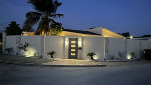 Une maison moderne avec une entrée bien éclairée, une façade en pierre et un palmier en arrière-plan.