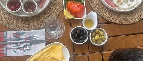 A table set with various food items including bread, hot dogs, and fruits, suggesting a casual dining experience.