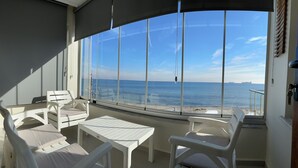 A balcony with white furniture, a table, and a view of the sea and ships. - Kingway Suite (Tekirdag)