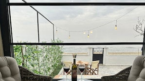 A cozy outdoor seating area with wicker chairs and a round table, overlooking a beach. - Kingway Suite (Tekirdag)