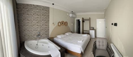 A modern bedroom with a large bed, a separate bathroom with a bathtub, a small desk, and a chair.